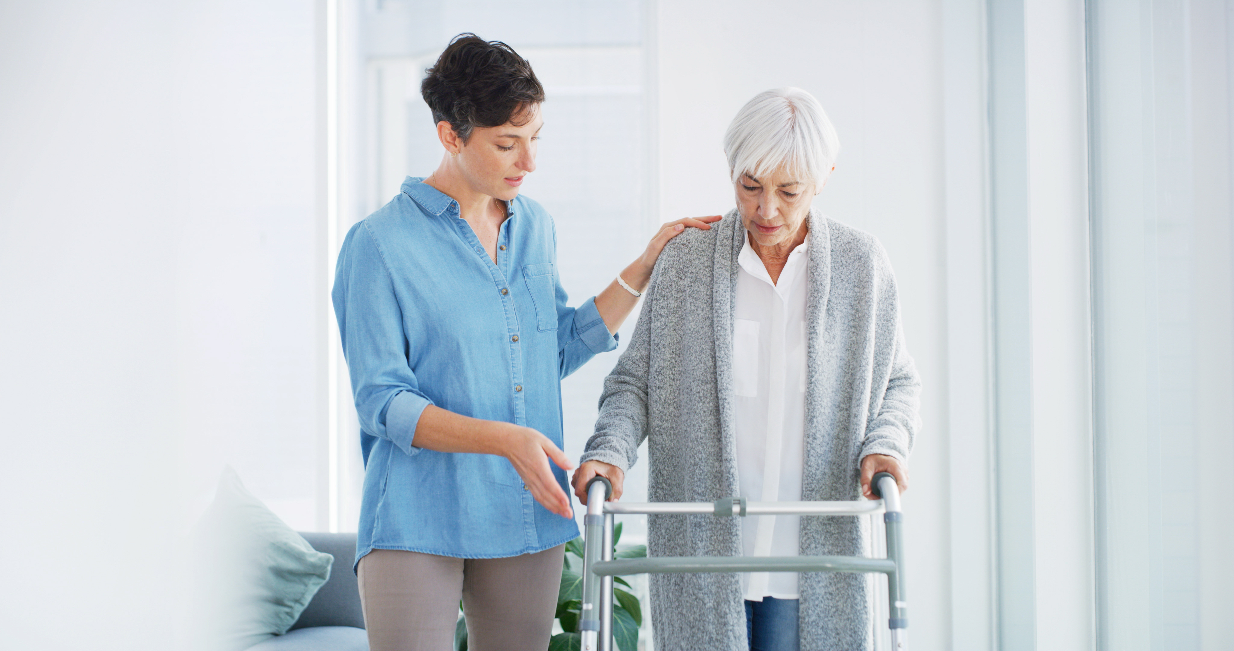 Caregiver assisting elderly person with walker